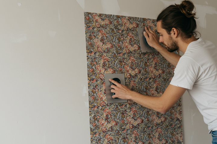 Une photo montrant   une personne appliquer de papier peint sur plaques de plâtre